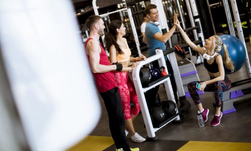 Group of young people in sportswear talking in a gym after a workout