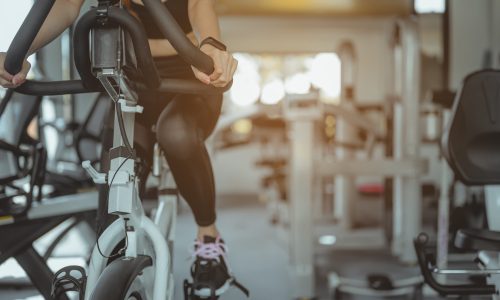 Front view of woman workout with bike. Women exercise working out in the gym for healthy lifestyle on bike at sunset. Fitness ,workout, gym exercise ,lifestyle and healthy concept.