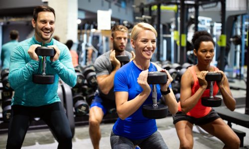 Group of sportive young people in gym. Happy fit friends workout, exercise in fitness club