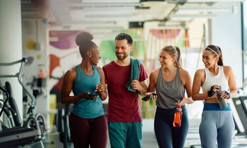 Young happy athletes communicating while walking through a gym after sports training.