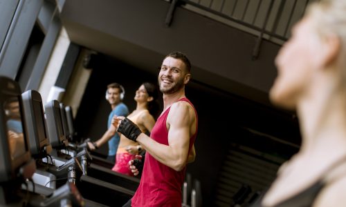 Group of young people running on treadmills in modern gym
