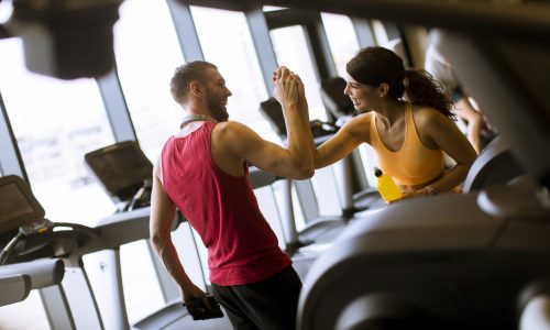 Young woman and personal male trainer rest in the gym after workout