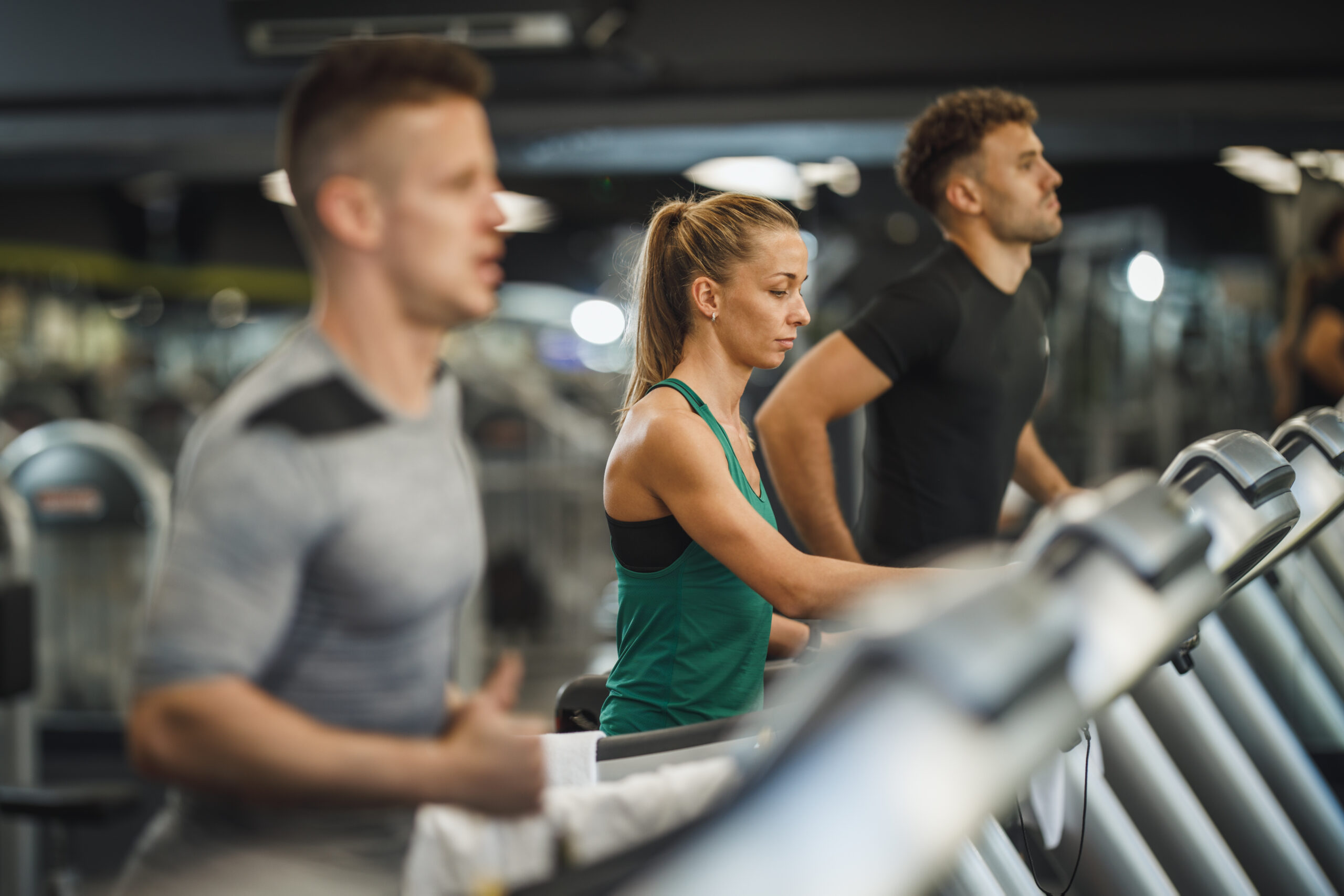 Shot of three young people exercising on a treadmill at the gym.