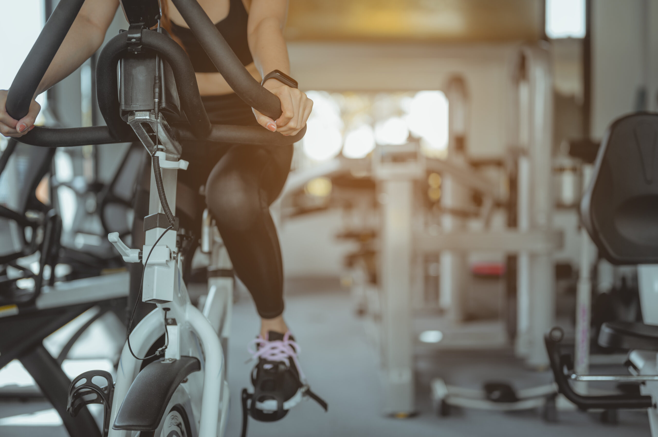 Front view of woman workout with bike. Women exercise working out in the gym for healthy lifestyle on bike at sunset. Fitness ,workout, gym exercise ,lifestyle and healthy concept.